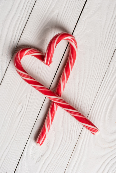 Draufsicht auf Weihnachtsbonbons in Form eines Liebessymbols auf Holzgrund - Foto, Bild