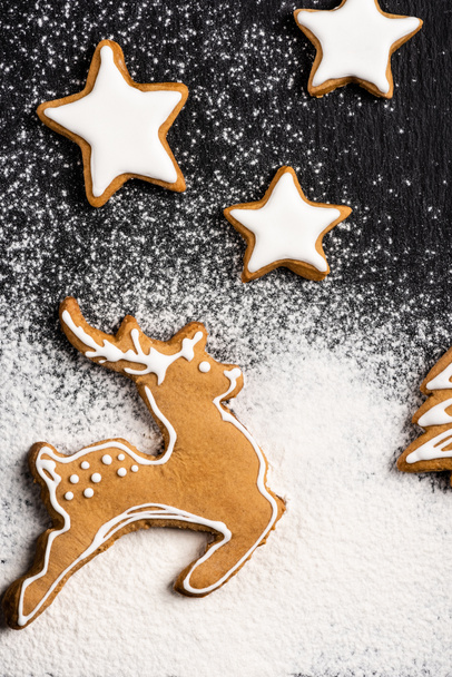 Top view of gingerbread cookies in shape of stars and deer with sugar powder - Foto, imagen