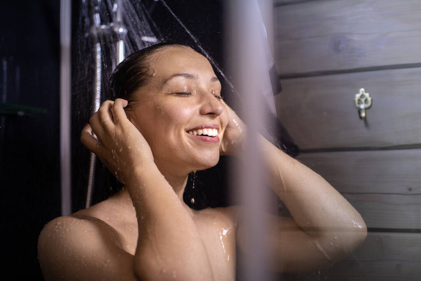 Vista lateral da mulher bonita feliz lava corpo e cabelo desfrutando de tomar banho - Foto, Imagem