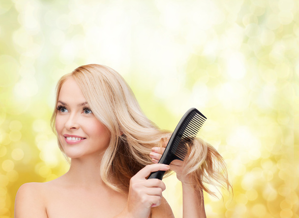 Smiling woman with hair brush - 写真・画像