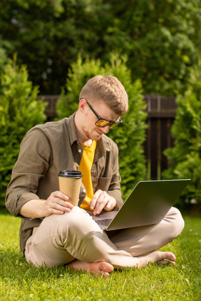 Jeune étudiant de sexe masculin millénaire faisant ses devoirs en utilisant la connexion wifi à l'extérieur - Photo, image