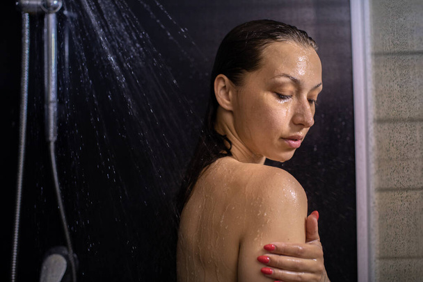 обнаженная девушка, наслаждающаяся текущей водой, принимающая душ в ванной, закрывая глаза - Фото, изображение