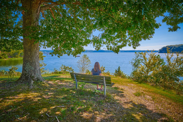 Women sitting on a bench enjoying the scenery of Kentucky Lake. - Zdjęcie, obraz