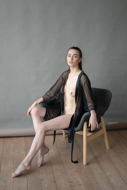 young beautiful woman posing nude in the studio, sitting on a chair - Photo, Image