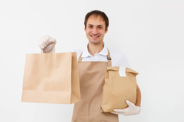 consegna uomo lavorando in camicia con grembiule e guanti protettivi mano tenendo pacco isolato sfondo bianco - Foto, immagini