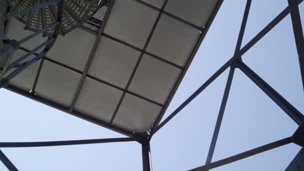 Спиральная лестница из цельной стали в тени, снятая снизу вверх с камерой, панорамная с платформы слева от лестницы, голубое небо на заднем плане, 4k UHD, 25p - Кадры, видео