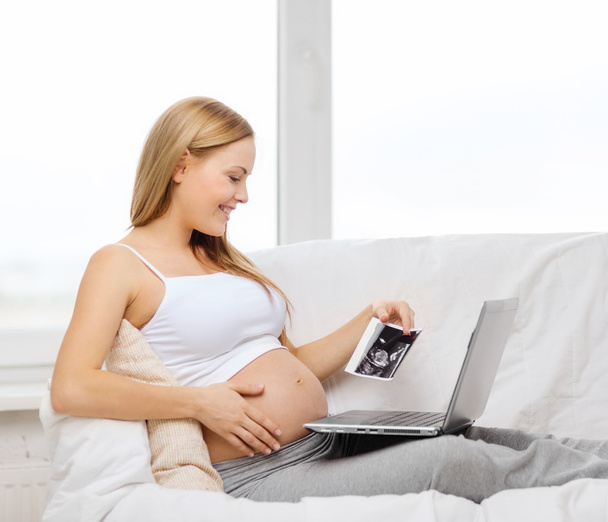 Smiling pregnant woman with laptop computer - 写真・画像