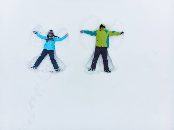 ζευγάρι που διασκεδάζουν κάνοντας χιόνι άγγελος κορυφή άποψη - Φωτογραφία, εικόνα
