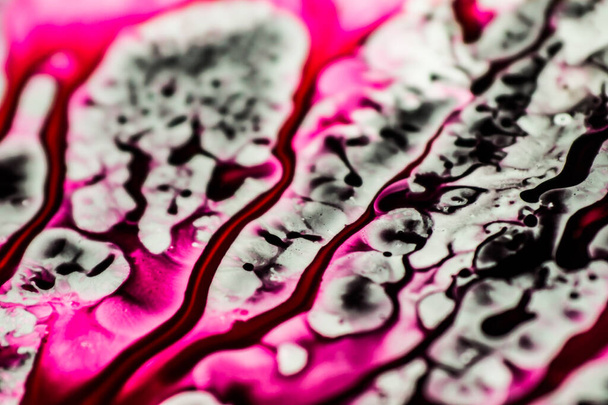 Zwarte en roze navulinkt gemorst op de witte gootsteen en de inkt gemengd in abstracte blobs en patronen. - Foto, afbeelding