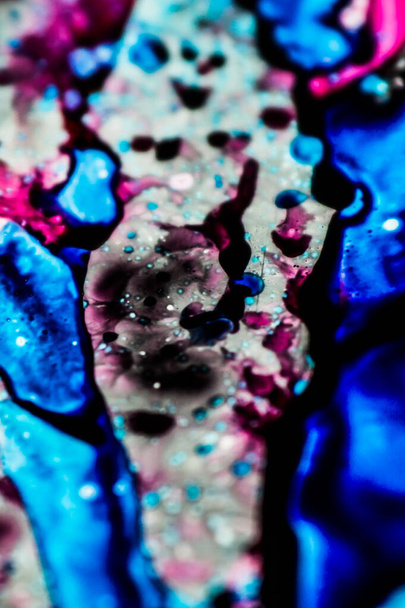 Blauwe en roze navulinkt gemorst op de witte wastafel en de inkt gemengd in abstracte blobs en patronen. - Foto, afbeelding