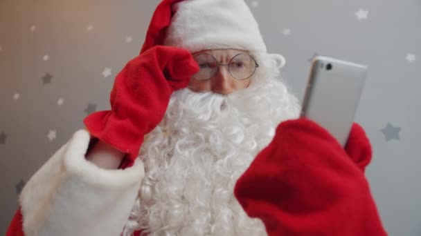 Serious guy in Santa outfit using smartphone touching screen on starry background - Πλάνα, βίντεο