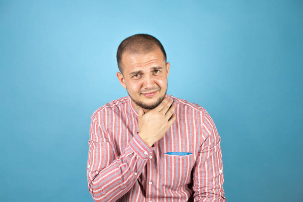 Ρώσος επιχειρηματίας που φοράει κόκκινο πουκάμισο πάνω από μπλε φόντο αγγίζοντας τον επώδυνο λαιμό, πονόλαιμο για γρίπη, θρόμβο και μόλυνση - Φωτογραφία, εικόνα