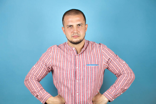 Російський бізнесмен над синім фоном скептичний і нервовий, не схвалюючи вираз обличчя з руками в поясі - Фото, зображення
