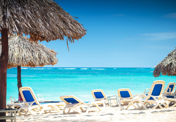 Тропічний вид на пляж з парасольками і пляжними кріслами
 - Фото, зображення