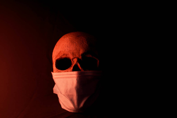 κρανίο με χειρουργική μάσκα πορτοκαλί τόνος με μαύρο φόντο - Φωτογραφία, εικόνα