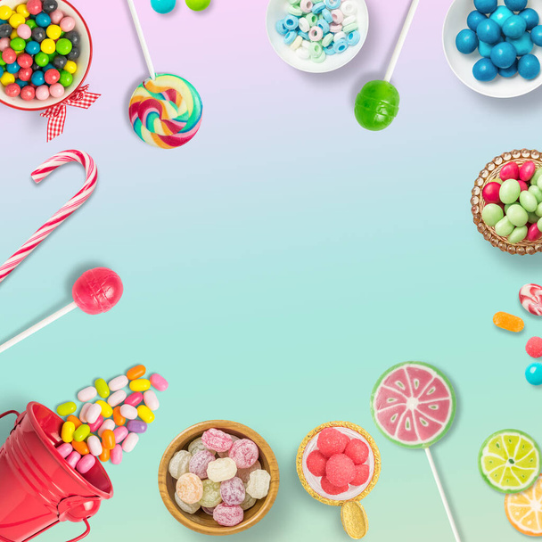 Snoepjes, chocolaatjes en lolly 's op een zachte regenboog achtergrond met kopieerruimte. Achtergrond, banner o achtergrond met zoetigheden. Bovenaanzicht van kleurrijke zoetigheden. - Foto, afbeelding
