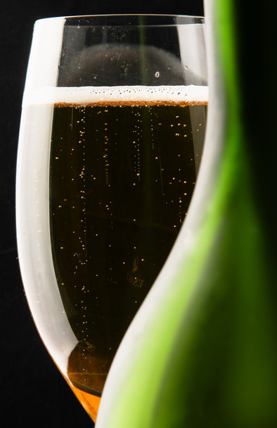A glass of champagne near a bottle - Фото, изображение