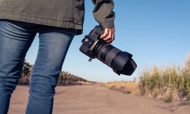 Woman holding an SLR camera from behind - Photo, Image