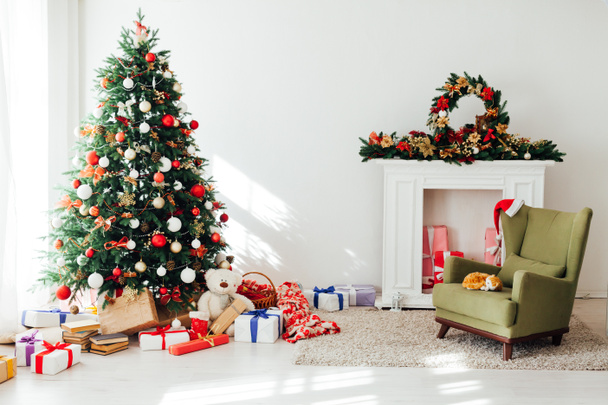 Pino árbol de Navidad con regalos de luces de guirnalda para el nuevo año en el interior de la habitación blanca como telón de fondo - Foto, imagen