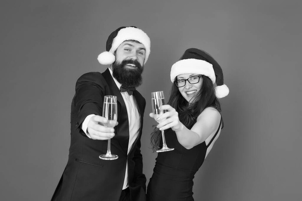 Lets have fun. Office party. Couple at corporate party. Happy new year. Bearded businessman in tuxedo and girl elegant dress drinking sparkling wine red background. Winter party. Merry christmas - Foto, afbeelding
