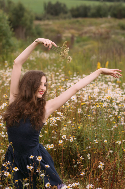Giovane bella ragazza tiene mazzo di fiori in mano e danza in campo camomilla in estate - Foto, immagini