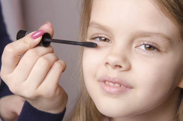 Makeup artist paints eyelashes on girl's face - Φωτογραφία, εικόνα