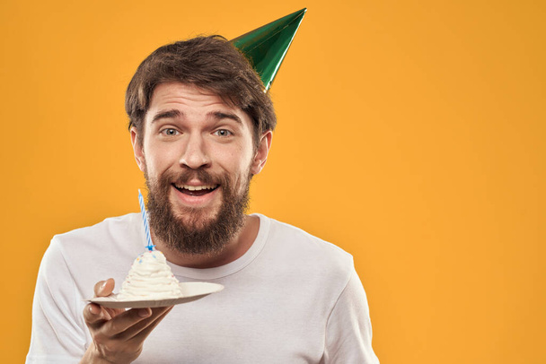 Vousatý muž s dortem a v čepici oslavující jeho narozeniny - Fotografie, Obrázek
