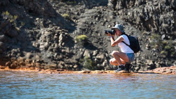 Um fotógrafo com câmera DSLR andando pelo rio e montanhas. - Foto, Imagem