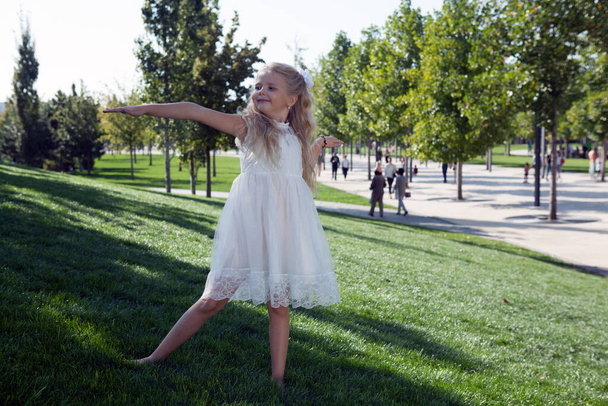 маленькая девочка в белом платье в зеленом саду - Фото, изображение