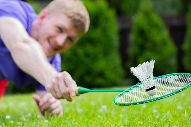 Fit männlicher Athlet Badmintonspieler fliegt über Gras in Sprung, Aktion, Bewegung - Foto, Bild