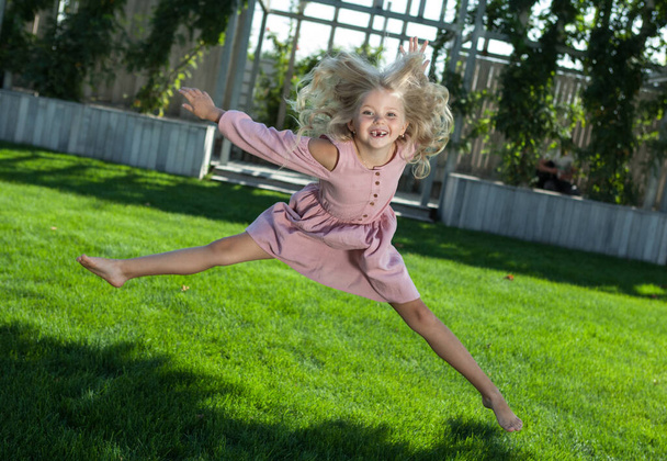 menina alegre em um vestido rosa saltando retrato - Foto, Imagem