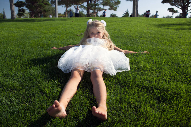 pieni tyttö löysä hiukset mekko sijaitsee vihreällä ruoholla - Valokuva, kuva