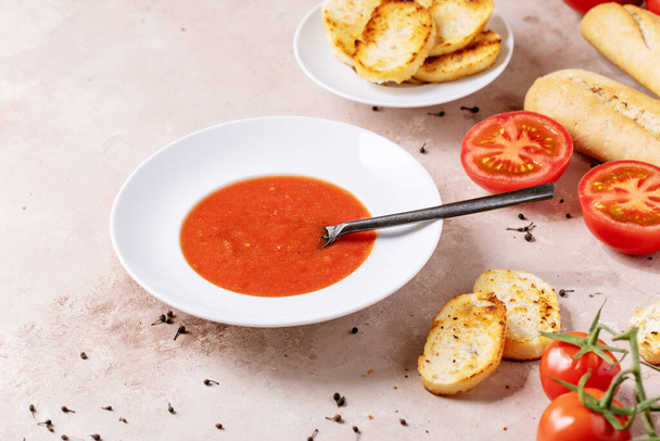 Homemade tomato soup served with fresh bio tomatoes and bread over white texture background - Photo, image