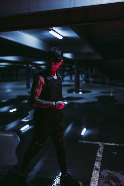 Tattooed man in the night parking lot. Cyberpunk style. Guy with cyber technology. - Photo, Image