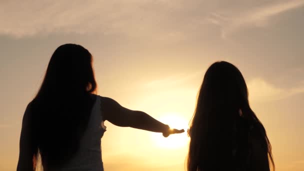 Szczęśliwa mama i córka na polu o zachodzie słońca. Córka i matka wyciągają ręce do słońca. koncepcja szczęśliwej rodziny dzieci. Matka i dziecko spacerują po parku - Materiał filmowy, wideo
