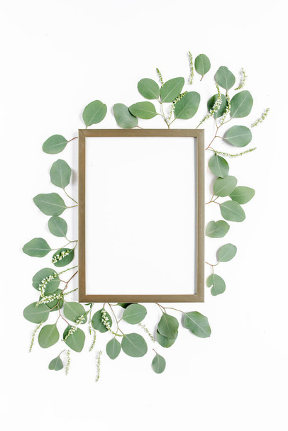 Square gold frame decorated with green eucalyptus leaves, twigs, floral pattern on a white background. The apartment lay, top view. Floral frame.  - Photo, image