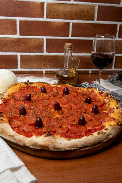 Смачна піца Пепероні на дерев'яному столі. Піца Пепероні - свіжа піца з перцем, сиром моцарела, чорними оливками та томатним соусом
 - Фото, зображення