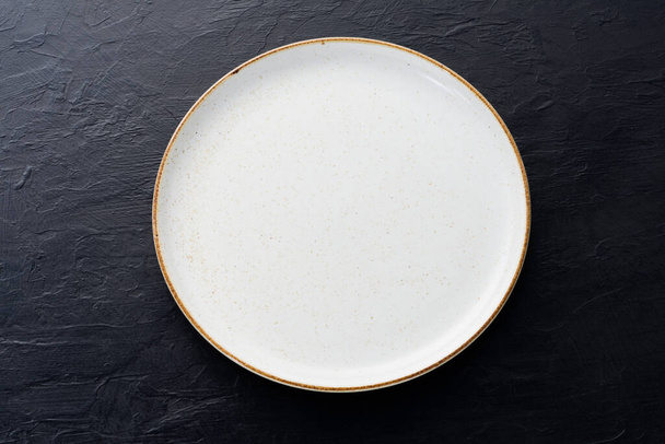 Empty white ceramic plates with spoons and forks arranged on an old black wooden table - top view. - 写真・画像