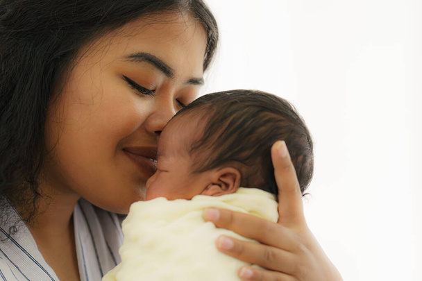 mixed race african american and asian mother gentle kiss her newborn baby with happy face - Photo, Image