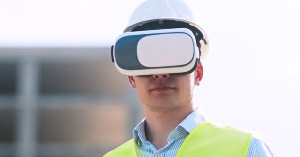 Engineer in VR glasses visualizing building plan at construction site, using interface of future, tracking shot - Footage, Video
