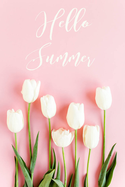 Hello summer text, white tulips on pink background. Minimal floral concept greeting card. Flat lay, top view. - Foto, afbeelding