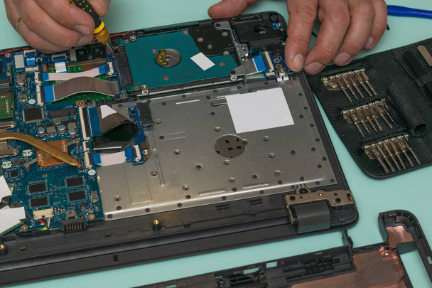 Un homme remplace un disque dur sur un ordinateur portable. - Photo, image