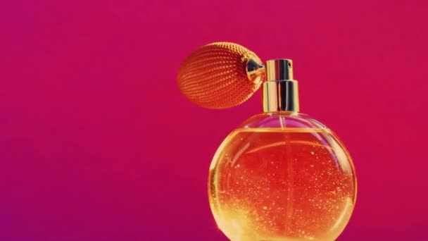 Goldene Duftflasche und leuchtende Lichterketten auf rosa Hintergrund, glamouröser Parfümduft als Urlaubsparfümerieprodukt für Kosmetik- und Schönheitsmarken - Filmmaterial, Video