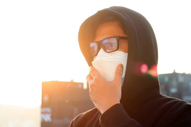 Aasian ihmiset käyttävät naamioita suojellakseen koronavirusta auringonlaskua, lämmintä sävyä ja pehmeää tarkennusta vastaan - Valokuva, kuva