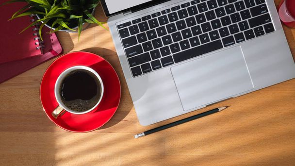 Draufsicht auf Arbeitstisch mit Laptop, Kaffeetasse und Bürozubehör auf Holztischhintergrund - Foto, Bild
