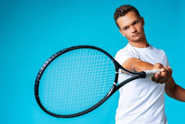 Young man tennis player in sportswear posing against blue background - Foto, Imagem
