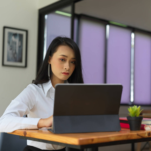 Portrait de travailleuse de bureau travaillant avec une tablette numérique sur une table de travail en bois dans une pièce de bureau  - Photo, image