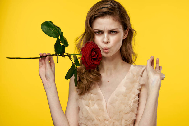 Романтична жінка в вечірній сукні з червоною трояндою на жовтому тлі обрізаний портрет
 - Фото, зображення