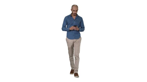 Man text messaging while walking on white background. - Foto, Imagem