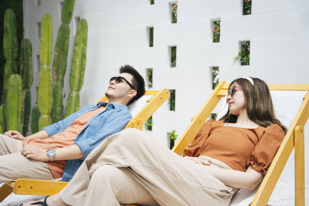 Asian couple traveler wearing sunglasses sitting on beach chair. - Photo, Image
